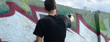 Genç mecnuna beton duvara grafiti boyar. Yasadışı vandalizm kavramı. Sokak sanatı.