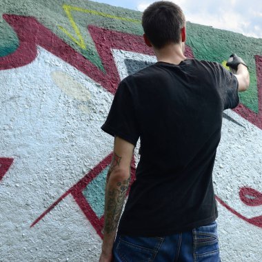Genç mecnuna beton duvara grafiti boyar. Yasadışı vandalizm kavramı. Sokak sanatı.