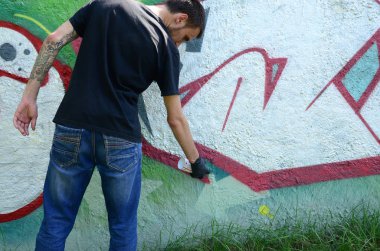 Genç mecnuna beton duvara grafiti boyar. Yasadışı vandalizm kavramı. Sokak sanatı.
