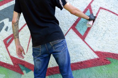 Genç mecnuna beton duvara grafiti boyar. Yasadışı vandalizm kavramı. Sokak sanatı.