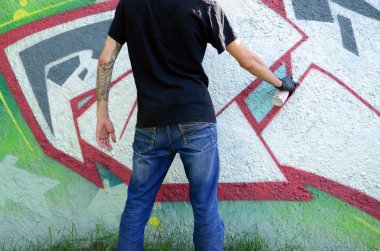 Genç mecnuna beton duvara grafiti boyar. Yasadışı vandalizm kavramı. Sokak sanatı.