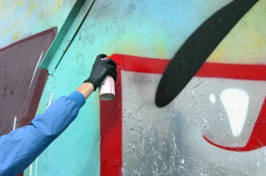 Genç mecnuna gizli yüzü olan bir metal duvar grafiti boyar. Yasadışı vandalizm kavramı.