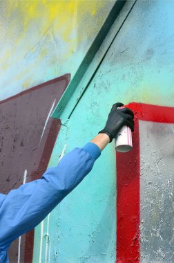 Bir el bir sprey ile yeni bir grafiti duvara çekiyor olabilir. Metal bir duvara bir grafiti çizim işlemi fotoğrafı. Sokak sanatı ve yasadışı vandalizm kavramı.