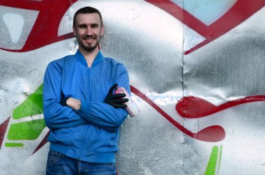 Grafiti sanatçısı sprey ile pozlar renkli boyalı duvar arka planı olabilir. Sokak sanatı kavramı.