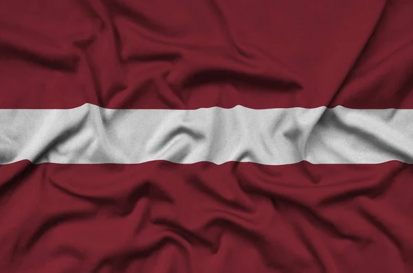 Latvia flag  is depicted on a sports cloth fabric with many folds. Sport team waving banner
