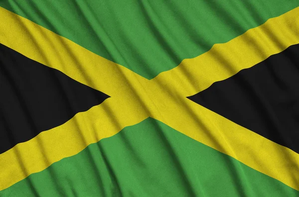 ジャマイカ国旗は 多くのひだを持つスポーツの布生地に描かれています スポーツ チームを振ってバナー — ストック写真