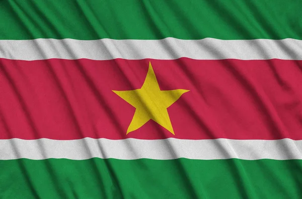 Suriname flag  is depicted on a sports cloth fabric with many folds. Sport team waving banner