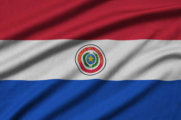 Парагвайский флаг изображен на спортивной ткани со множеством складок. Спортивная команда размахивает баннером
