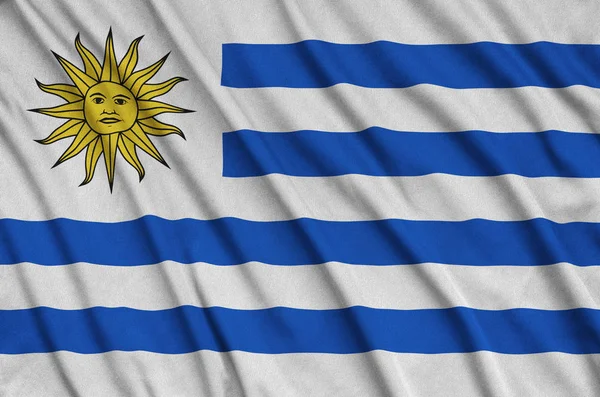 ウルグアイの国旗は 多くのひだとスポーツの布生地に描かれています スポーツ チームを振ってバナー — ストック写真
