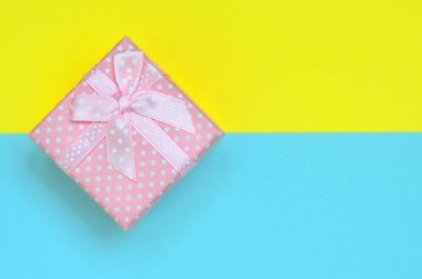 Küçük pembe hediye kutusu yalan doku arka planda moda pastel mavi ve sarı renkler kağıt en az kavramında.
