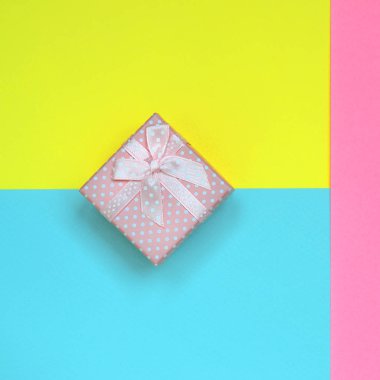 Küçük pembe hediye kutusu yalan doku arka planını moda pastel mavi, sarı ve pembe kağıt en az renkleri konsept üzerine.