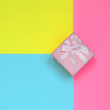 Küçük pembe hediye kutusu yalan doku arka planını moda pastel mavi, sarı ve pembe kağıt en az renkleri konsept üzerine.