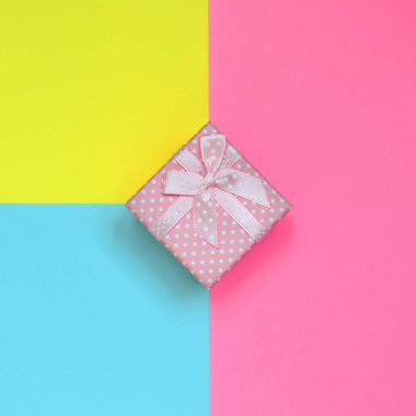 Küçük pembe hediye kutusu yalan doku arka planını moda pastel mavi, sarı ve pembe kağıt en az renkleri konsept üzerine.