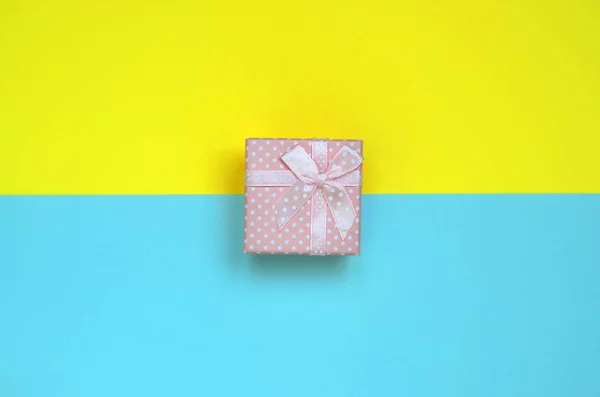 ファッション パステル ブルーと黄色のテクスチャ背景に小さなピンクのギフト ボックス嘘最小限概念で紙の色 — ストック写真