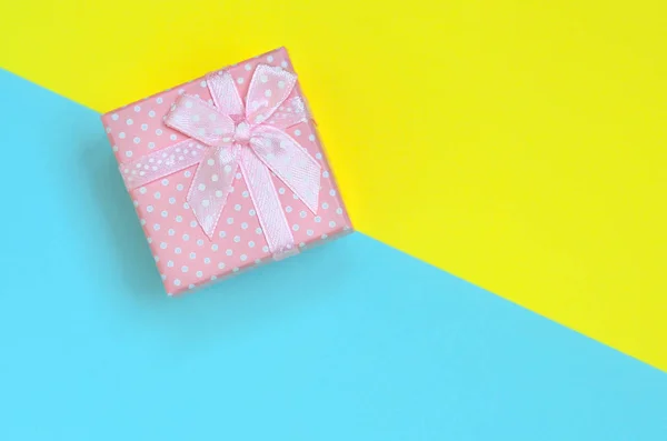 小粉色礼品盒位于时尚柔和的蓝色和黄色的颜色纸的纹理背景最小概念 — 图库照片