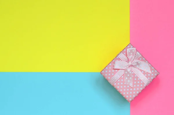 粉红色的小礼品盒躺在纹理背景的时尚粉彩蓝色 黄色和粉红色的颜色纸在最小的概念 — 图库照片