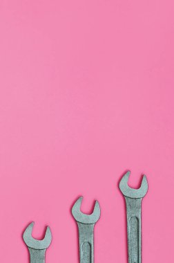 Üç metalik somun anahtarları moda pastel pembe renkli kağıt doku arka plan üzerinde en az düzeyde kavram yalan..