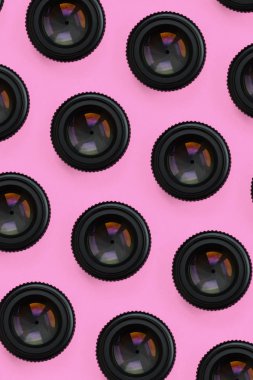 Bir kaç kamera lensler kapalı bir diyafram ile moda pastel pembe renkli kağıt doku arka plan üzerinde en az düzeyde kavram yalan. Soyut trendy desen.