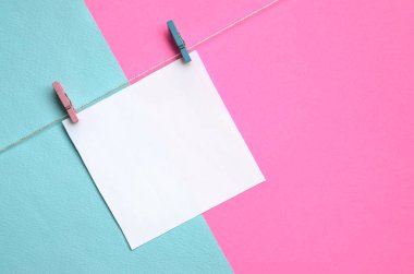 Bir parça kağıda mandal moda pastel mavi arka plan doku üzerinde bir ip üzerinde asılı ve pembe renkler en az kavramında kağıt.