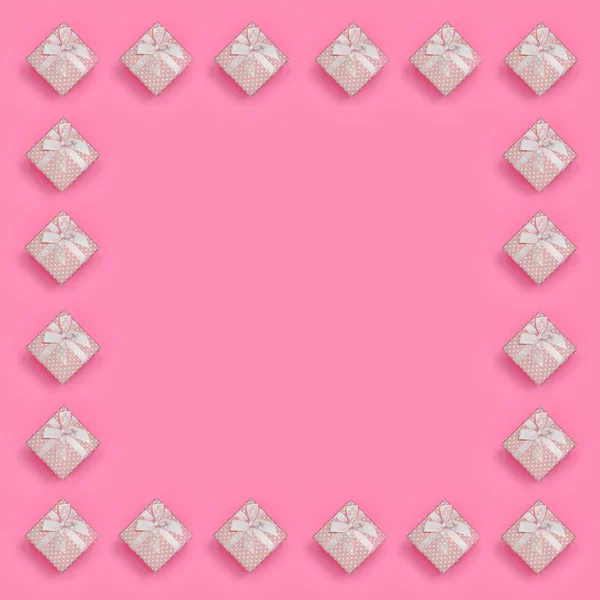 Pembe hediye kutuları çerçevesinde moda pastel pembe renkli kağıt doku arka plan üzerinde en az kavramında yatıyor. Soyut trendy desen.