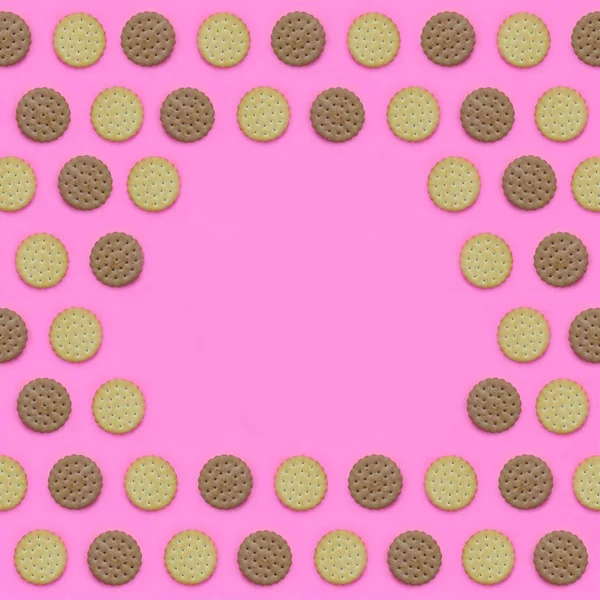 Frame of a brown biscuits on a pink background. Trendy minimal concept of food and dessert. Abstract flat lay, top view.