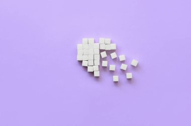 Kırık bir kalp kesme şeker yapılmış bir trendy pastel menekşe arka plan üzerinde yatıyor.