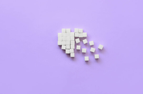 A broken heart made of sugar cubes lies on a trendy pastel violet background.