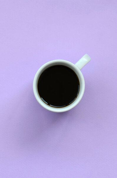 Small white coffee cup on texture background of fashion pastel violet color paper in minimal concept.