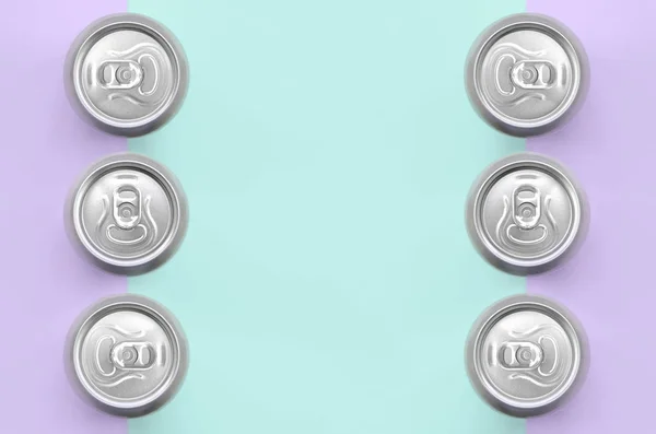 Many metallic beer cans on texture background of fashion pastel violet and blue colors paper in minimal concept.