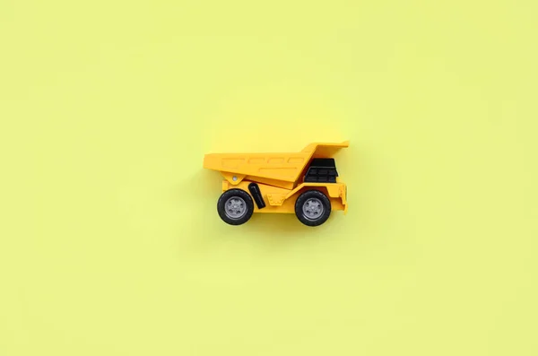 小黄色玩具卡车在纹理背景的时尚淡黄色纸的最小概念 — 图库照片