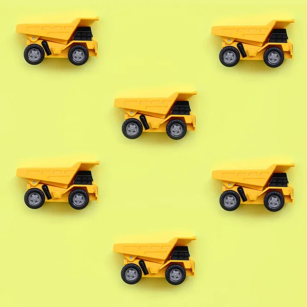 Many small yellow toy trucks on texture background of fashion pastel yellow color paper in minimal concept.