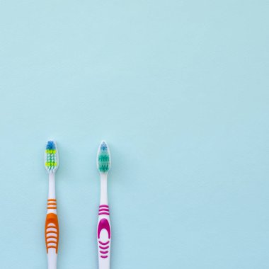 İki diş fırçaları pastel mavi bir arka plan üzerinde yalan. Üstten görünüm, düz yatıyordu. En az kavramı.