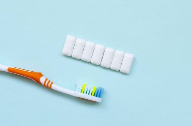 Diş fırçası ve çiğneme diş etleri pastel mavi bir arka plan üzerinde yalan. Üstten görünüm, düz yatıyordu. En az kavramı.