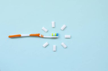 Diş fırçası ve çiğneme diş etleri pastel mavi bir arka plan üzerinde yalan. Üstten görünüm, düz yatıyordu. En az kavramı.