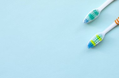 İki diş fırçaları pastel mavi bir arka plan üzerinde yalan. Üstten görünüm, düz yatıyordu. En az kavramı.