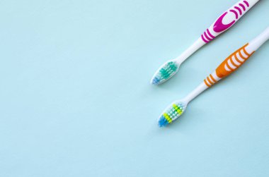 İki diş fırçaları pastel mavi bir arka plan üzerinde yalan. Üstten görünüm, düz yatıyordu. En az kavramı.
