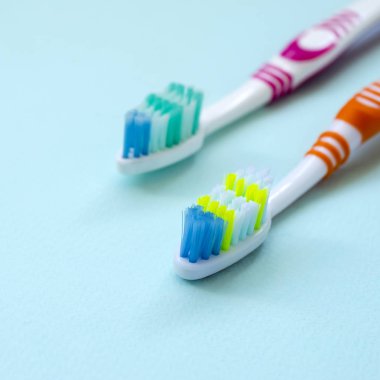 İki diş fırçaları pastel mavi bir arka plan üzerinde yalan. Üstten görünüm, düz yatıyordu. En az kavramı.