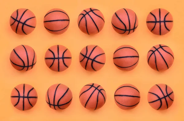 Many small orange balls for basketball sport game lies on texture background of fashion pastel orange color paper in minimal concept.