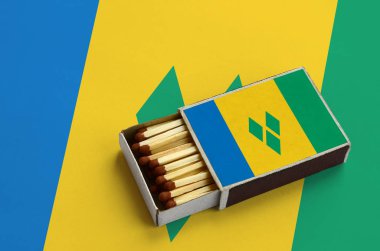 Saint Vincent ve Grenadinler bayrak açık bir kibrit kutusu içinde gösterilen hangi dolu maçlar ve büyük bir bayrak üzerinde yatıyor.