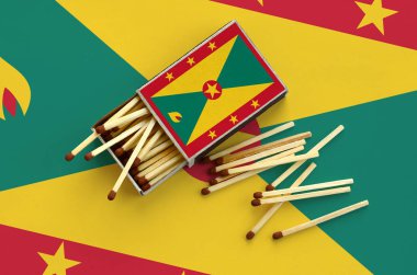 Grenada bayrağı bir kibrit kutusu içinden birkaç sonbahar eşleşir ve büyük bir bayrak üzerinde yatıyor açık gösterilir.