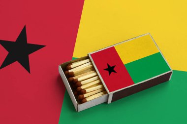 Gine Bissau bayrak açık bir kibrit kutusu içinde gösterilen hangi dolu maçlar ve büyük bir bayrak üzerinde yatıyor.