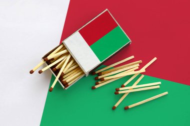 Madagaskar bayrağı bir kibrit kutusu içinden birkaç sonbahar eşleşir ve büyük bir bayrak üzerinde yatıyor açık gösterilir.