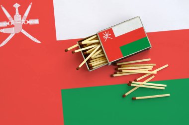 Umman bayrağı bir kibrit kutusu içinden birkaç sonbahar eşleşir ve büyük bir bayrak üzerinde yatıyor açık gösterilir.