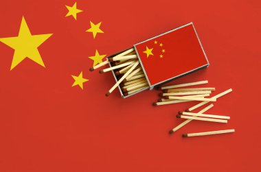 Çin bayrağı bir kibrit kutusu içinden birkaç sonbahar eşleşir ve büyük bir bayrak üzerinde yatıyor açık gösterilir.