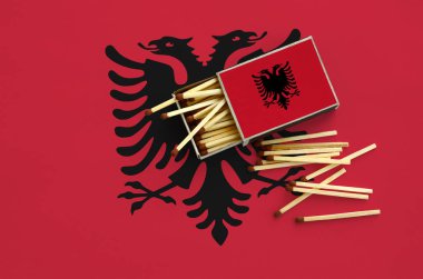  Arnavutluk bayrağı bir kibrit kutusu içinden birkaç sonbahar eşleşir ve büyük bir bayrak üzerinde yatıyor açık gösterilir.