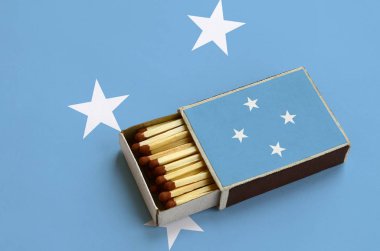 Mikronezya bayrak açık bir kibrit kutusu içinde gösterilen hangi dolu maçlar ve büyük bir bayrak üzerinde yatıyor.