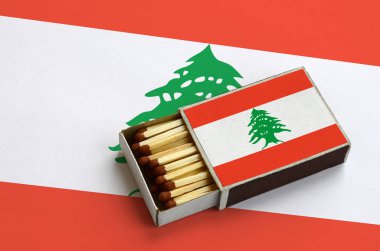 Lübnan bayrağı açık bir kibrit kutusu içinde gösterilen hangi dolu maçlar ve büyük bir bayrak üzerinde yatıyor.