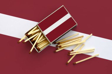 Letonya bayrağı bir kibrit kutusu içinden birkaç sonbahar eşleşir ve büyük bir bayrak üzerinde yatıyor açık gösterilir.