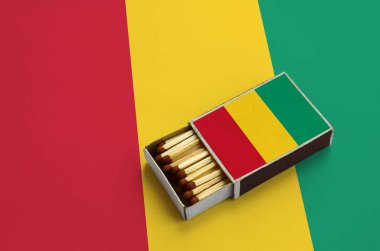 Gine bayrağı açık bir kibrit kutusu içinde gösterilen hangi dolu maçlar ve büyük bir bayrak üzerinde yatıyor.