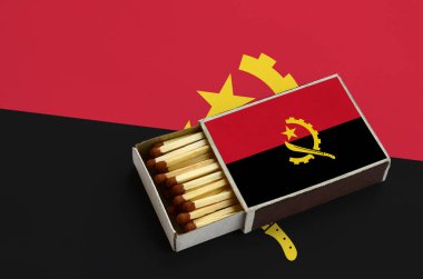 Angola bayrağı açık bir kibrit kutusu içinde gösterilen hangi dolu maçlar ve büyük bir bayrak üzerinde yatıyor.